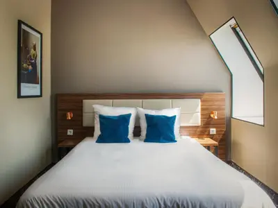 a bedroom with a large bed with blue pillows at Amsterdam Lake Hotel in Badhoevedorp
