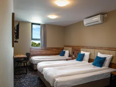 a hotel room with three beds with blue pillows at Amsterdam Lake Hotel in Badhoevedorp