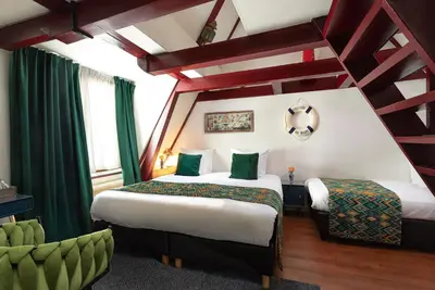 two beds in a hotel room with green curtains at Boutique Hotel des Arts in Amsterdam