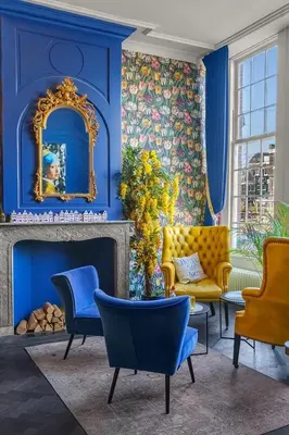 a living room with blue walls and a gold mirror at Boutique Hotel des Arts in Amsterdam