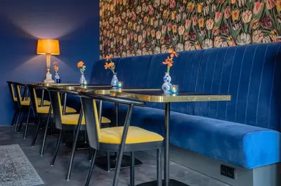 a row of tables with yellow chairs and a blue bench at Boutique Hotel des Arts in Amsterdam
