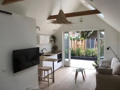 a room with a kitchen and a living room with a tv at Dune Vieuw in Zandvoort
