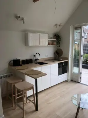 a kitchen with white cabinets and a table and chairs at Dune Vieuw in Zandvoort