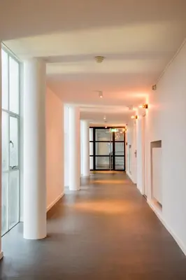 an empty hallway in an office building with white walls and columns at Gooiland Hotel in Hilversum