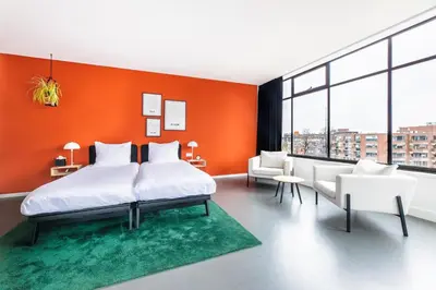 a bedroom with orange walls and a bed and chairs at Gooiland Hotel in Hilversum
