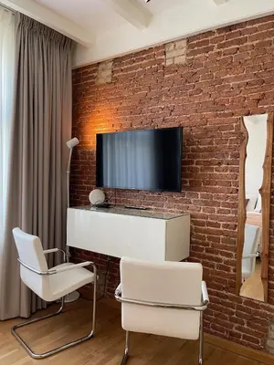 a living room with two chairs and a tv on a brick wall at Amsterdam-bnb in Amsterdam
