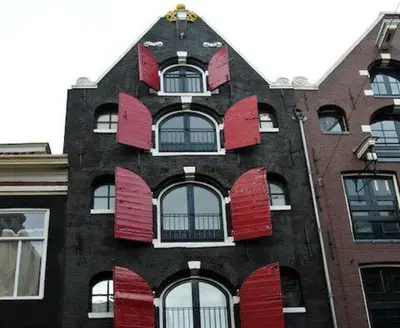 a building with red shutters on the side of it at Crown Guesthouse Amsterdam in Amsterdam