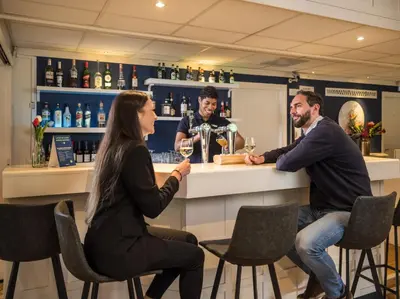 a man and a woman sitting at a bar at Campanile Hotel & Restaurant Gouda in Gouda