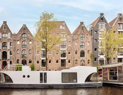 a boat in a canal in front of buildings at Cozy Cabin at houseboat in Amsterdam