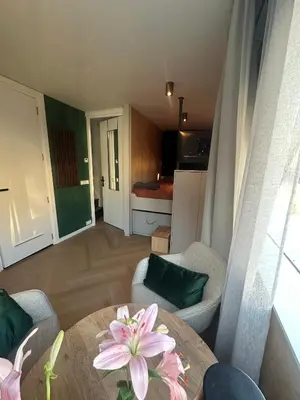 a living room with a table and a kitchen at Cozy Cabin at houseboat in Amsterdam