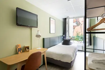 a bedroom with a bed and a desk and a tv at Hotel La Bohème in Amsterdam