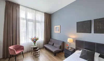 a bedroom with a bed and a couch and a window at Boutique Hotel Chariot - Amsterdam Schiphol Airport in Aalsmeer