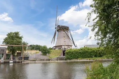 a windmill on the side of a river at Boutique Hotel Chariot - Amsterdam Schiphol Airport in Aalsmeer