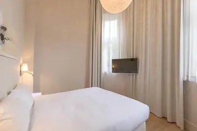 a bedroom with a white bed and a tv at Hotel Arena in Amsterdam