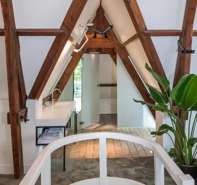 a room with wooden ceilings and a white chair at Hotel Arena in Amsterdam