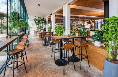 a restaurant with tables and chairs and plants at Hotel Arena in Amsterdam