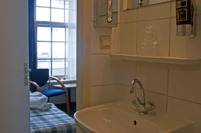 a bathroom with a sink and a chair and a window at Koopermoolen in Amsterdam