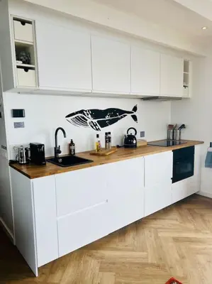 a kitchen with white cabinets and a wooden floor at Surla Houseboat 