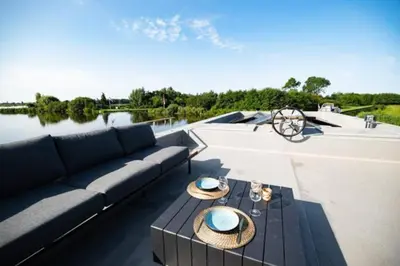a patio with a couch and a table on a roof at Surla Houseboat 