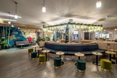 a restaurant with a bar with tables and green stools at Best Western Amsterdam in Amsterdam