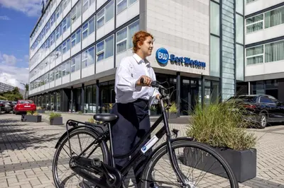 a man standing next to a bike in front of a building at Best Western Amsterdam in Amsterdam