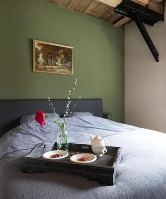 a tray with two plates and a vase with flowers on a bed at De Dinkelhoeve in Heemstede