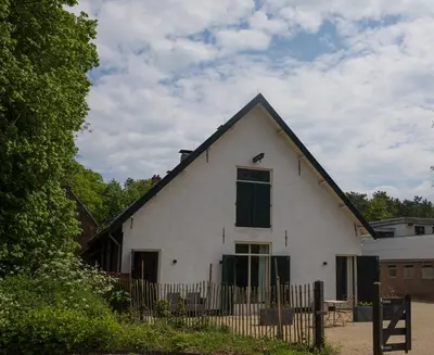 a white house with a black roof and a fence at De Dinkelhoeve in Heemstede