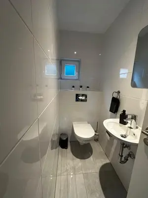 a white bathroom with a toilet and a sink at Ferienvilla 10 Minuten vom Strand in Dirkshorn