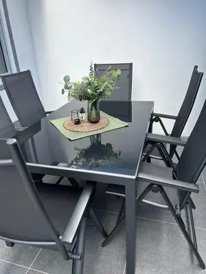 a table and chairs with a vase of flowers on it at Ferienvilla 10 Minuten vom Strand in Dirkshorn