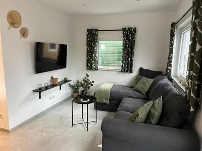 a living room with a couch and a tv at Ferienvilla 10 Minuten vom Strand in Dirkshorn