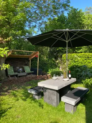 a picnic table with an umbrella in a yard at Ingeborgh Art Gastenverblijf in Grootschermer