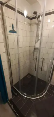 a shower in a bathroom with a black tiled floor at JONI, not for parties, not a hotel, room with no kitchen in Amsterdam