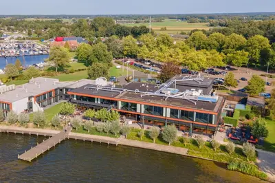 an aerial view of a building next to the water at Postillion Amersfoort Veluwemeer in Putten