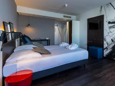 a bedroom with a large bed and a television at Postillion Amersfoort Veluwemeer in Putten