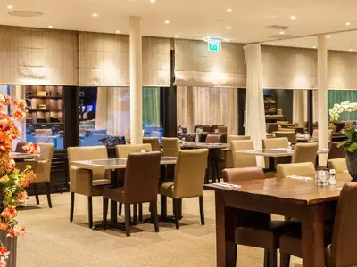 a dining room with tables and chairs in a restaurant at Postillion Amersfoort Veluwemeer in Putten