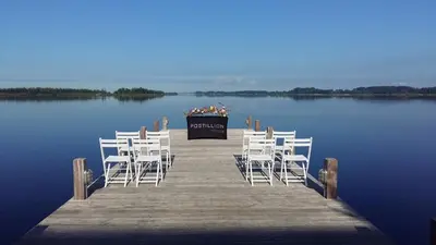 a dock with white chairs and a table on the water at Postillion Amersfoort Veluwemeer in Putten