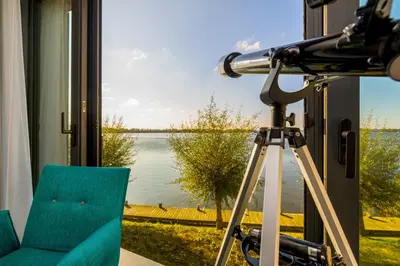 a camera on a tripod next to a window with a view at Postillion Amersfoort Veluwemeer in Putten