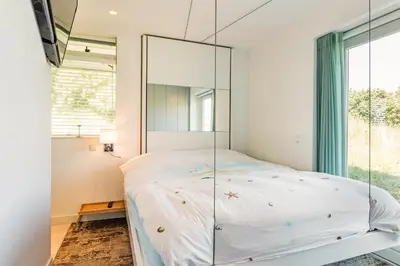 a bedroom with a mirrored bed and a window at Beach house Alba in Bergen aan Zee