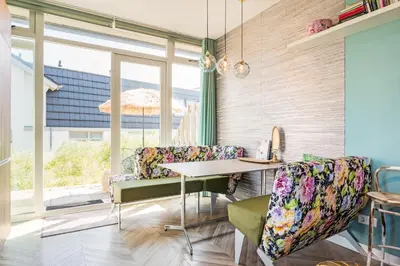 a dining room with windows and a table and chairs at Beach house Alba in Bergen aan Zee