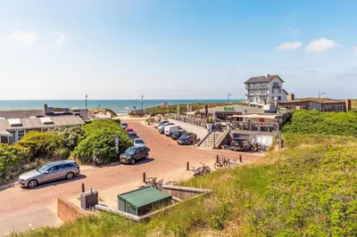 a group of cars parked in a parking lot next to the ocean at Beach house Alba in Bergen aan Zee