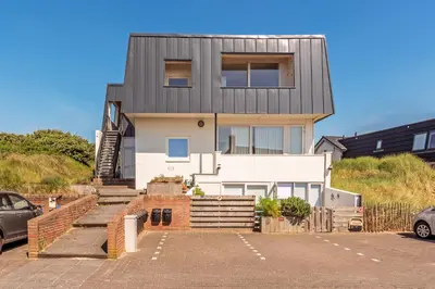 a house with a car parked in a parking lot at Beach house Alba in Bergen aan Zee