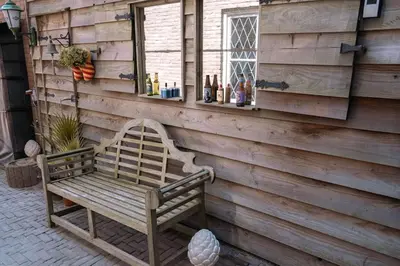a bench on the side of a wall with a window at 'T Heilige Pad in Egmond aan Zee