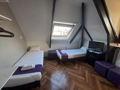 a small room with two beds and a window at Hotel Bellington in Amsterdam