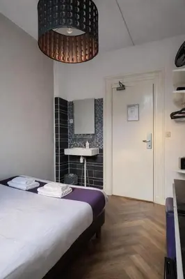 a bedroom with a bed and a bathroom with a sink at Hotel Bellington in Amsterdam