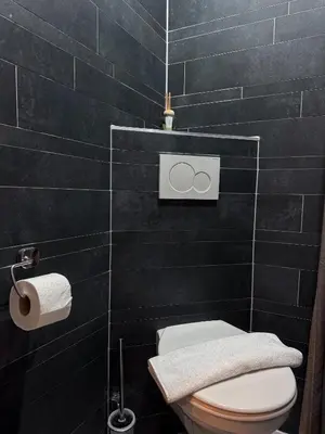 a bathroom with a toilet and a black tiled wall at Hotel Bellington in Amsterdam
