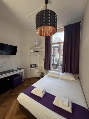 a bedroom with a large bed with two towels on it at Hotel Bellington in Amsterdam