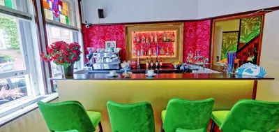 a bar in a restaurant with green chairs at De Bedstee Boutique Capsules in Amsterdam