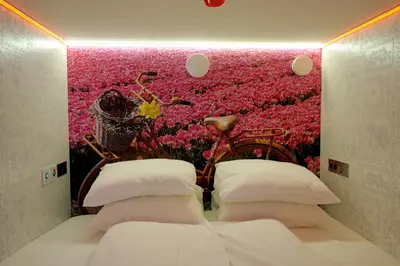 a bedroom with a pink wall with a bed and a bike at De Bedstee Boutique Capsules in Amsterdam