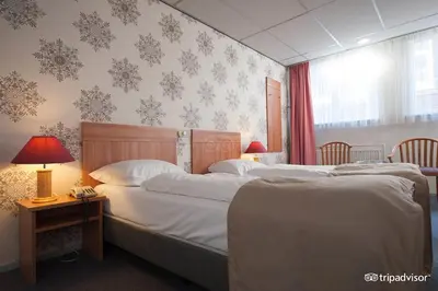a bedroom with two beds and a table with a lamp at Rho Hotel in Amsterdam