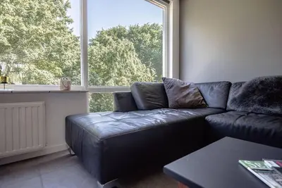 a living room with a leather couch and a large window at CityHouse Alkmaar in Alkmaar